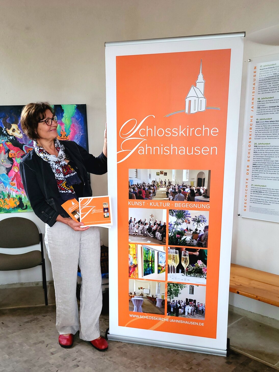Die Projektleiterin zeigt ein neues Rollup der Schlosskirche