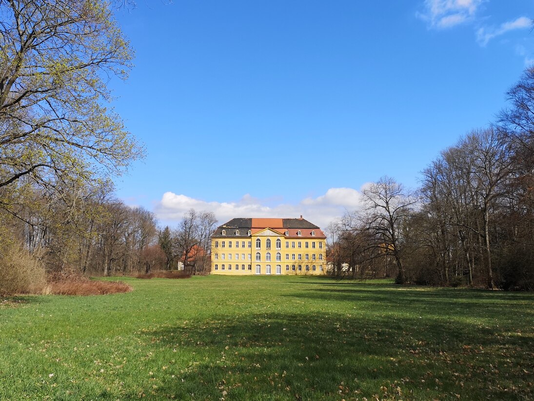 Blick vom Garten über eine Wiese zum Schloss