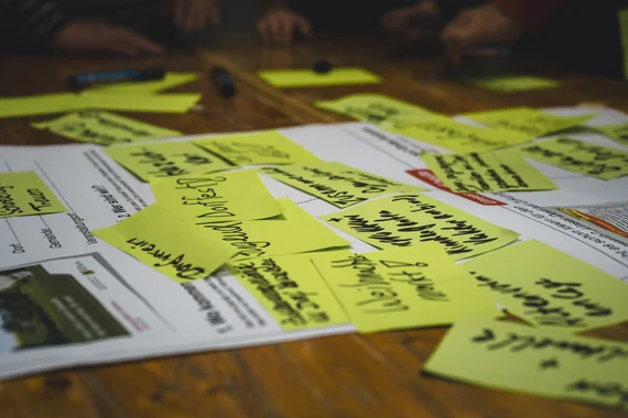 Auf einem Tisch liegt ein Formular und darauf grüne Zettel mit Ideenvorschlägen