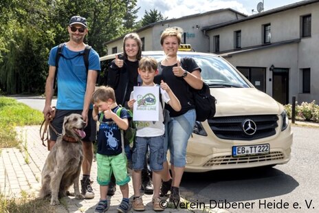 Familie mit drei Kindern und Hund vor dem Taxibus der Biberlinie