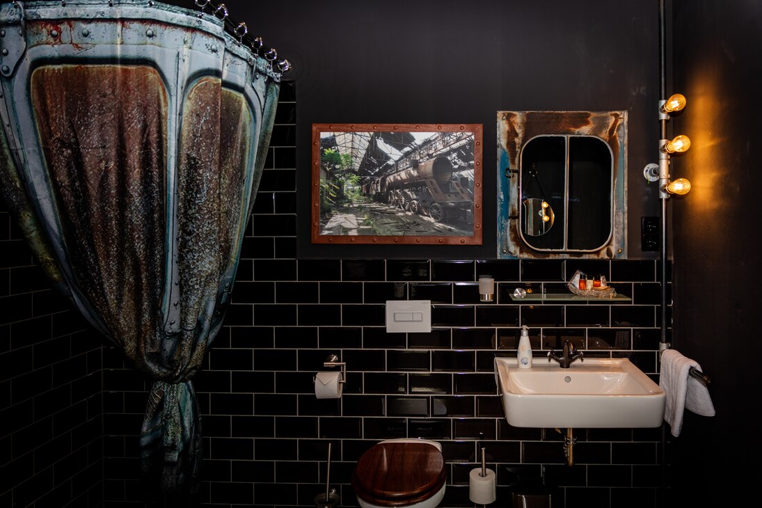 Blick in ein Badezimmer der Pension mit schwarzen Fliesen, gestaltet im Stil des Steampunks.
