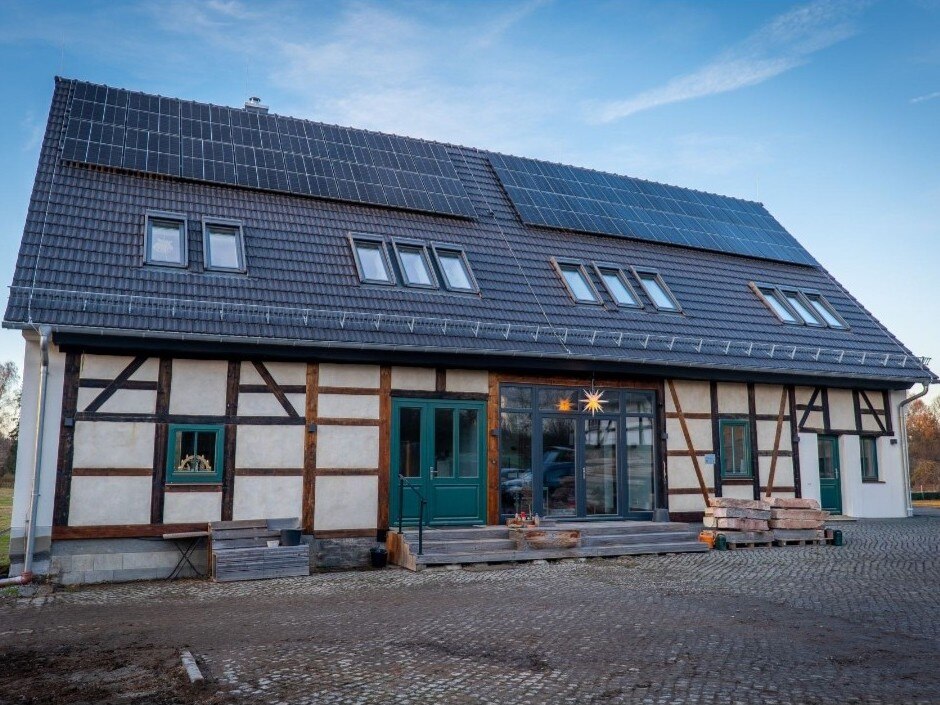 Vorderansicht der fertigen Wohnscheune mit Solarmodulen auf dem Dach