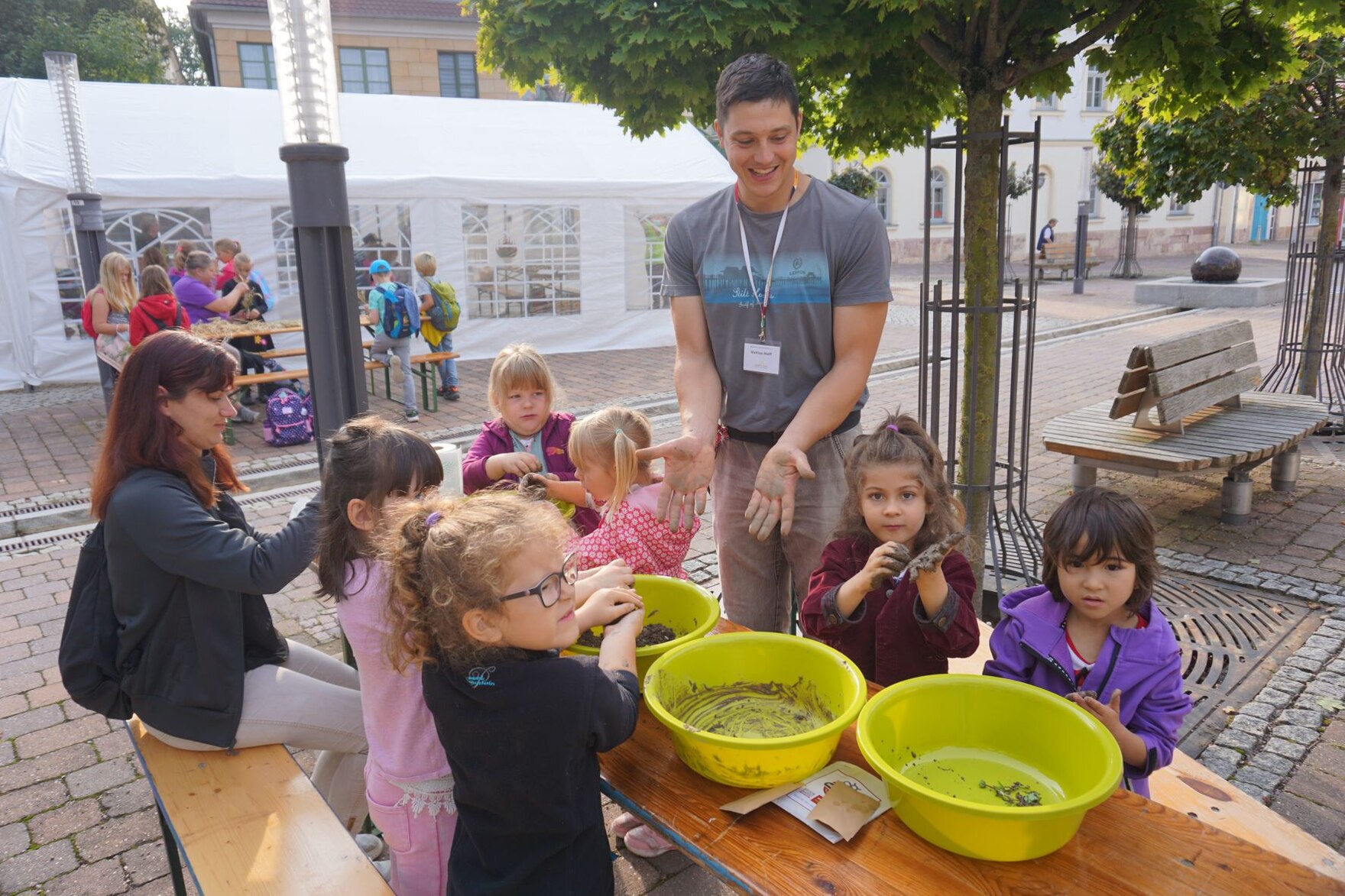 Kinder sitzen gemeinsam an einem Tisch mit Schüsseln und formen mit Ton