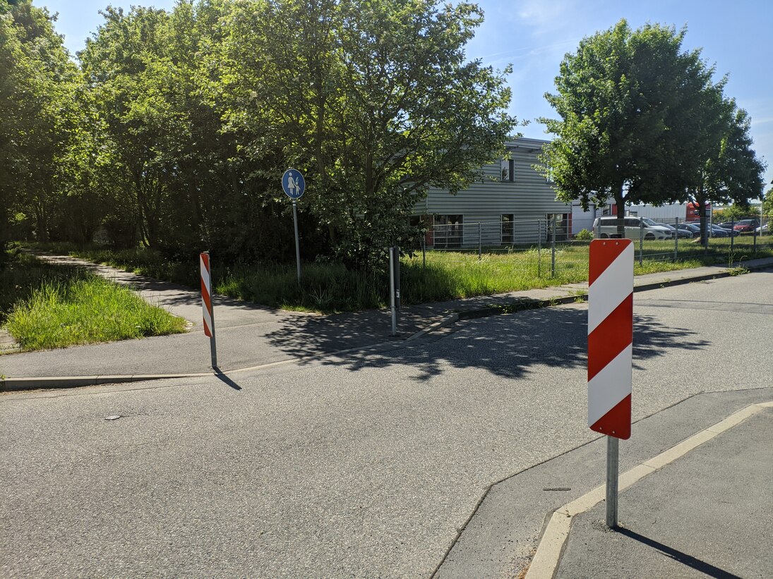 Querung des Skating-Rundwegs ist farblich abgesetzt und ragt von beiden Seiten in die Jakobsdorfer Straße, so dass diese beidseitig verengt wird. Die Einbuchtung des Skaterwegs wird von beiden Seiten durch Warnbaken markiert.
