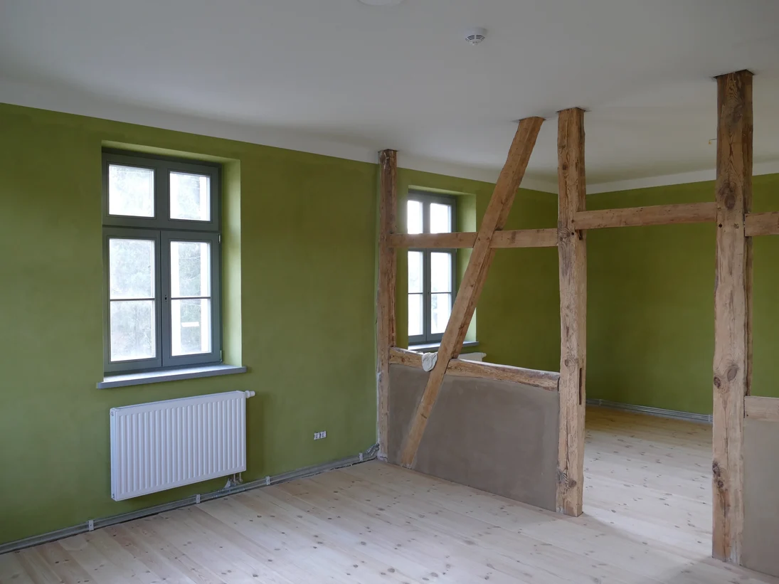 Raum mit grün gestalteten Wänden und offen liegenden Balken