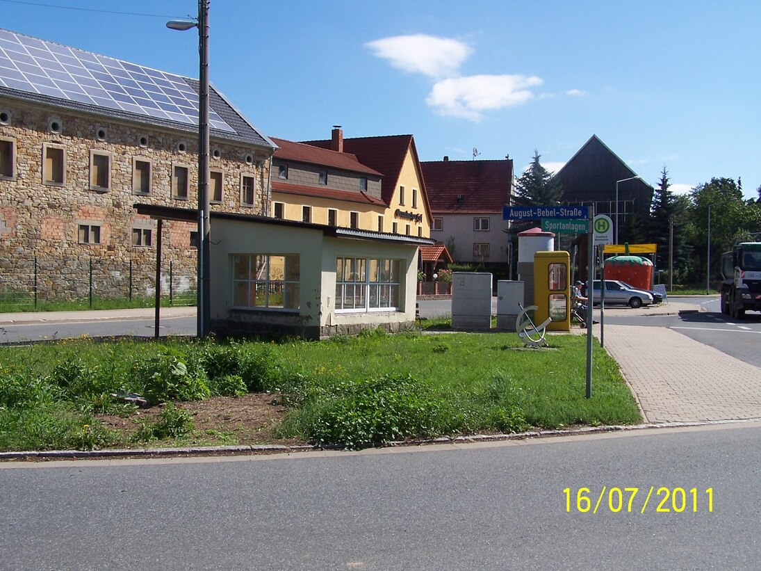 Ortsmitte vor der Maßnahme mit altem Straßenbelag und altem Buswartehaus in der Mitte